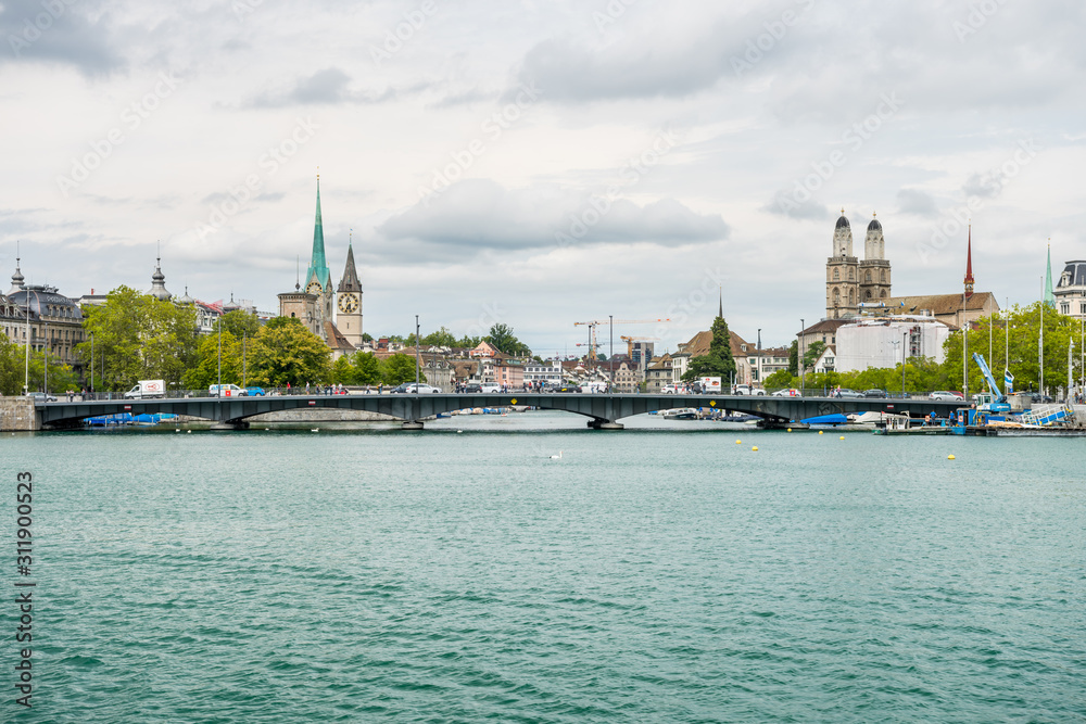 View of the historic buildings and bridge of Zurich at the bank of Limmat River and Zurich lake, with landmark of Fraumünster Church clock tower, Grossmunster (Great Church) and church  tower of St. P