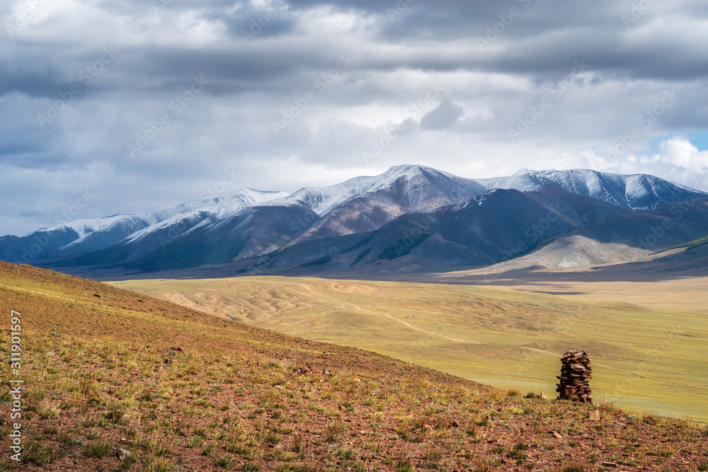 Cairn on a hillside. On the horizon is the Chikhachev Ridge, the border between Russia and Mongolia. Autumn. Kosh-Agach district, Altai Republic