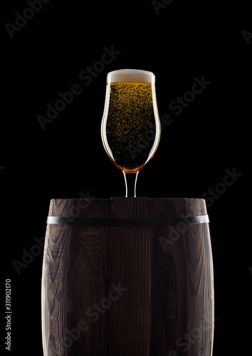 Cold glass of craft beer on old wooden barrel