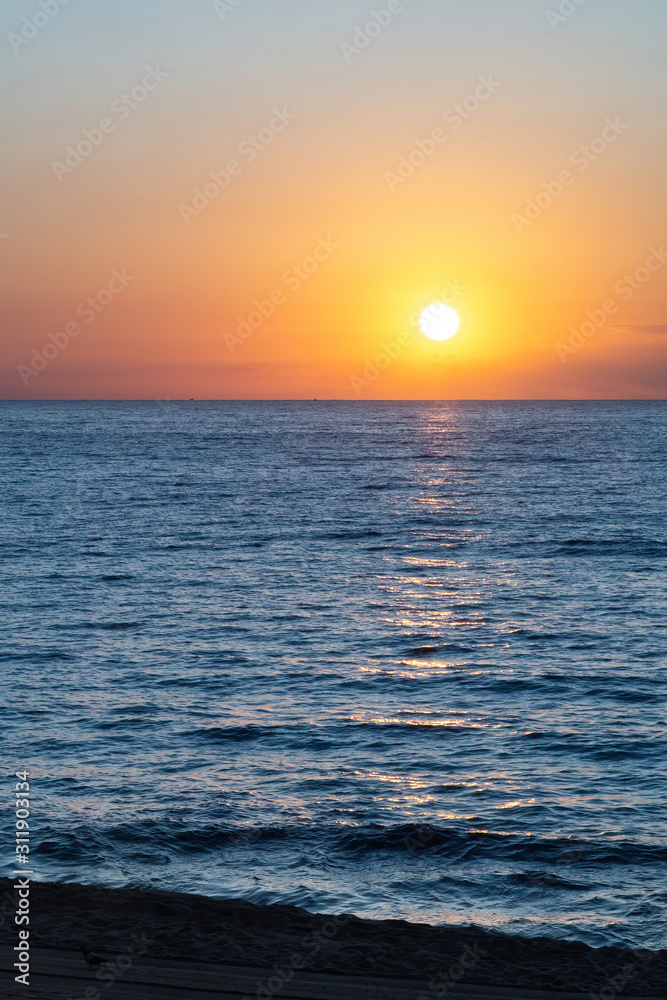Sun is rising above the calm blue sea.