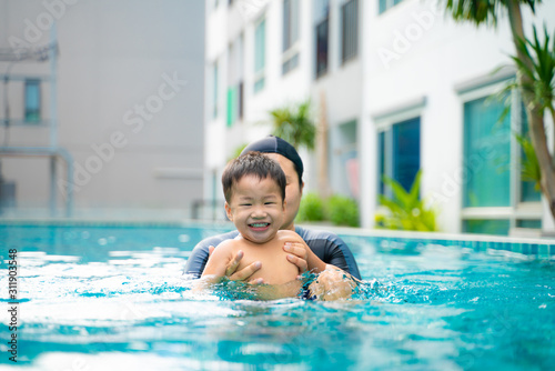 Young asian mother teach child boy swim lesson in pool