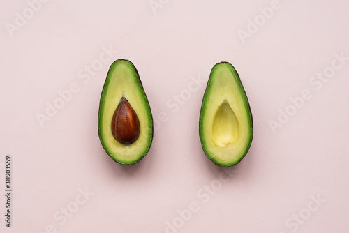 Avocado halves on pink background. Top view. Minimal summer food concept. Flat lay