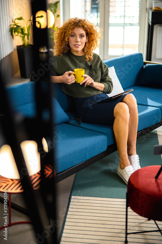 Relaxed female on sofa with gadget and hot drink stock photo
