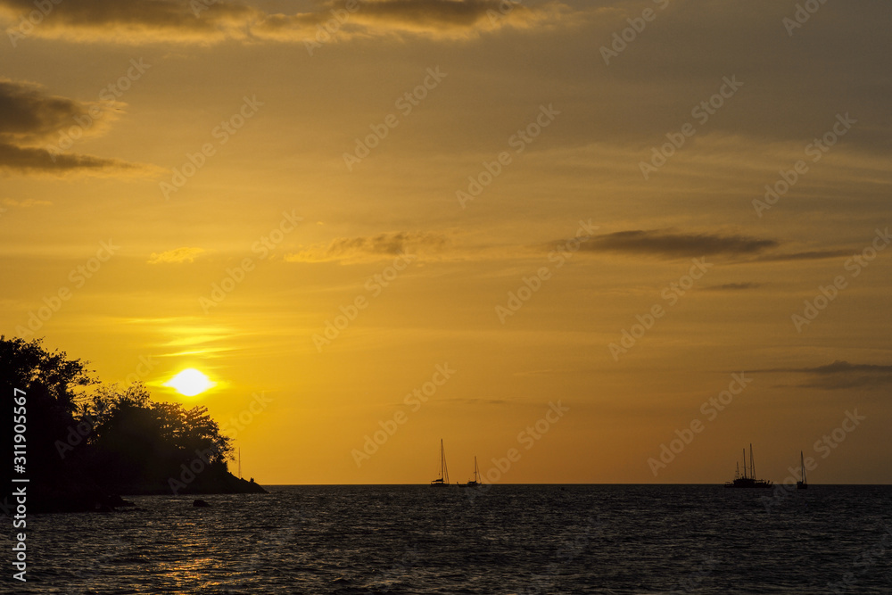 Silhouette of island and yacht boats on the horizontal line with light of sunset and twilight sky in background
