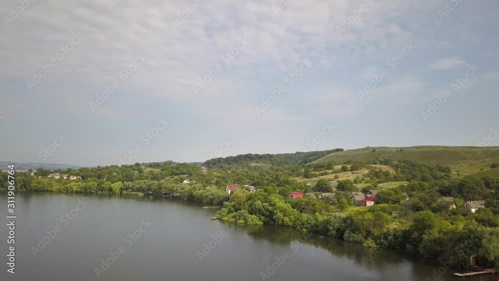 Aerial view of a small village in rural area between green trees on the shore of a big lake. Aerial view of a small village in rural area between green trees on the shore of a big lake.