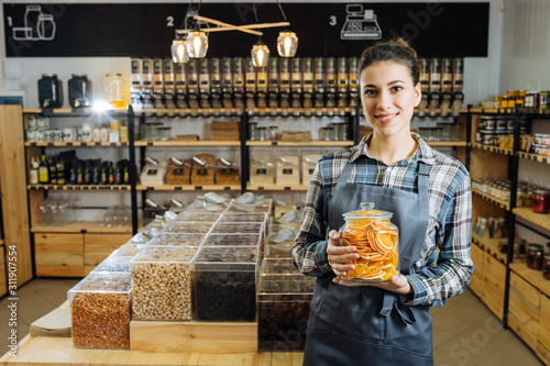 woman is bying products in zero waste shop with glass jars, cotton bags with out plastic packages photo