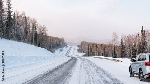 Winter landscape with silvery car standing on the roadside of mountain road. photo