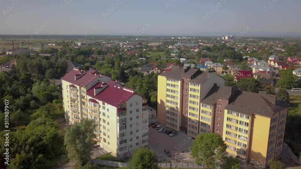 Aerial view of multistory apartment building in green residential area.