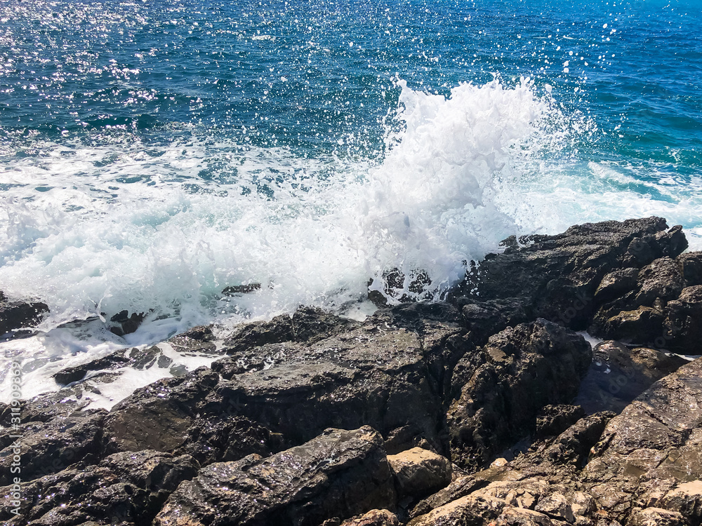 Waves crash on the rocks. Mediterranean sea in summer, storm and rocky shore