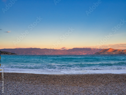 Sunset over spectacular blue sea and with illuminated mountain on the horizon