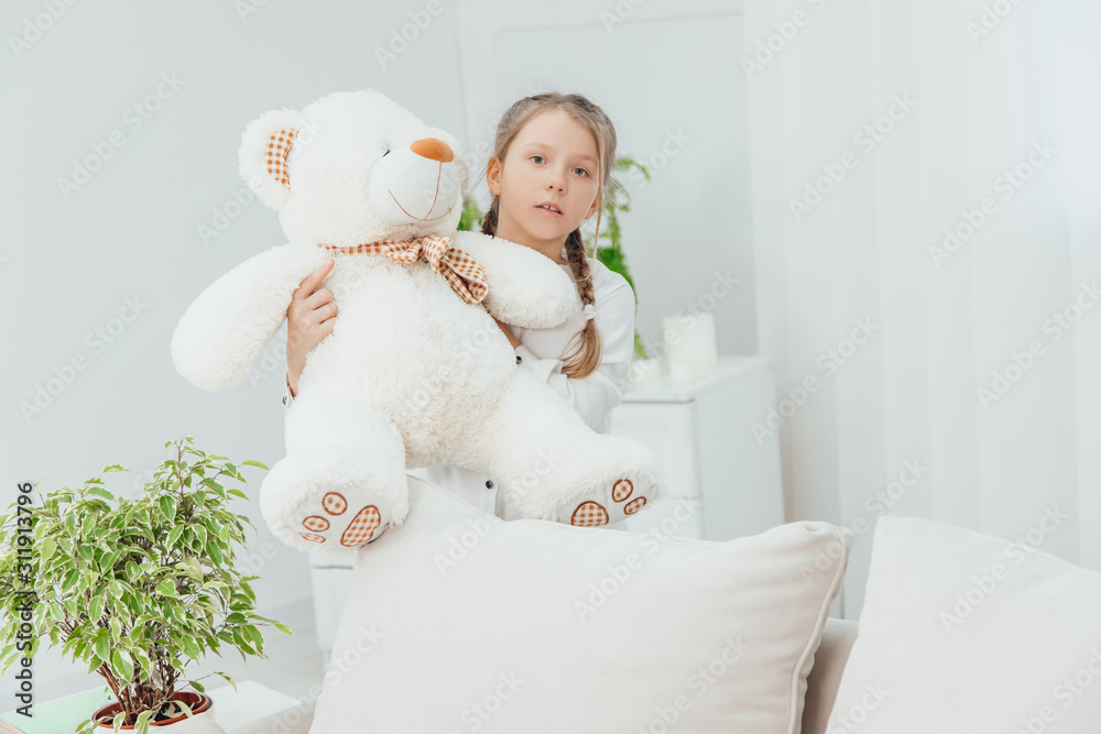 Adorable little girl standing with big white teddy-bear in her hands. A little bit worried face expression. Adorable little girl standing with big white teddy-bear in her hands. A little bit worried face expression.