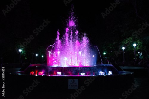 Drops scatter in the fountain with pink backlighting at night, close-up. Translation of the caption in the ad: "SWIMMING IN THE FOUNTAIN IS FORBIDDEN!"