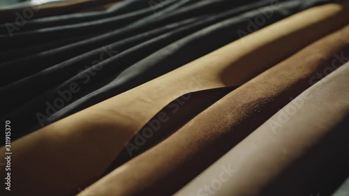 Rolls of leather in different colors on the table. Soft daylight falling on it. Closeup shot. 
