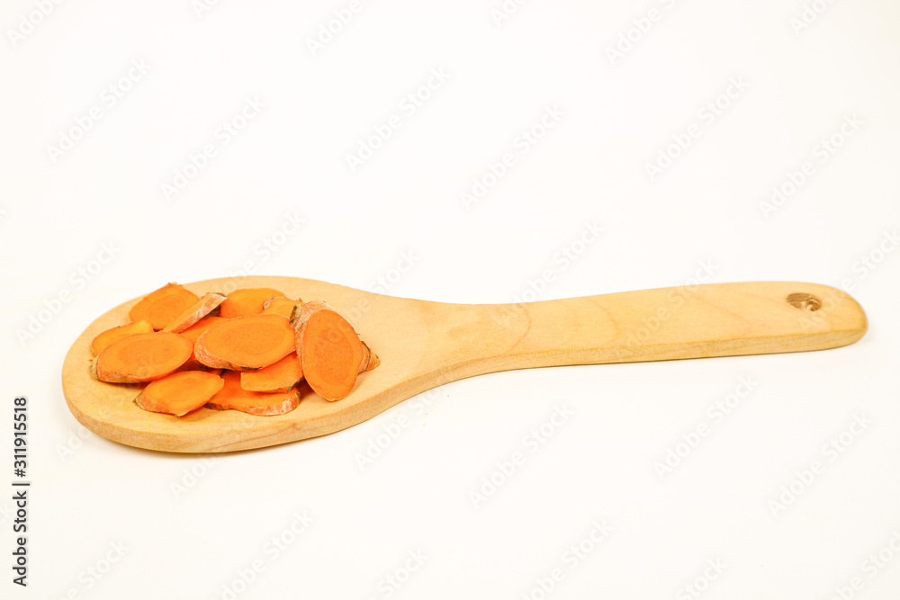 Turmeric rhizomes in a wooden spoon isolated on a white background Turmeric rhizomes in a wooden spoon isolated on a white background