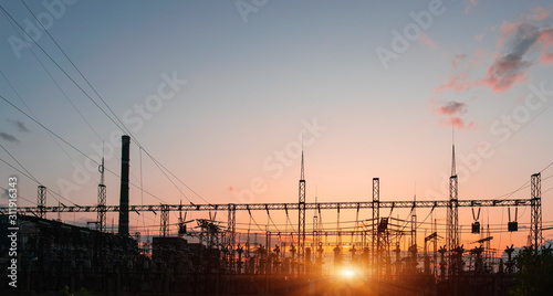 The silhouette of the evening electricity transmission pylon. Power transmission from a power plant to a city.