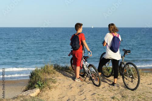 boy and young woman on a Bicycle on a cliff by the sea