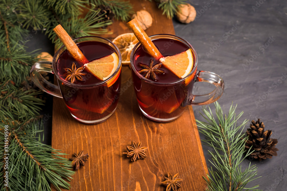 Christmas hot mulled wine with cardamom, cinnamon and anise on wooden background. against the background of fir branches, nuts and oranges Christmas hot mulled wine with cardamom, cinnamon and anise on wooden background. against the background of fir branches, nuts and oranges