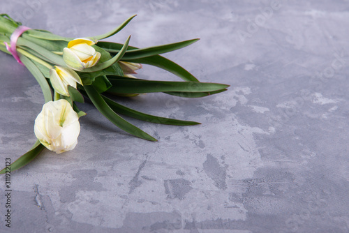 Fototapeta Naklejka Na Ścianę i Meble -  Fresh white spring tulips bouquet laying on grey plaster background