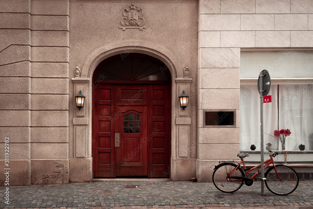 A bike parked outside a red old door with lights