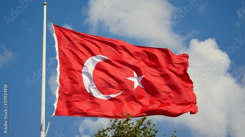 Turkish Flag waving in the wind over blue sky with white clouds. The flag of Turkey; A red flag featuring a white star and crescent often called as moon-star (Ayyildiz) photo