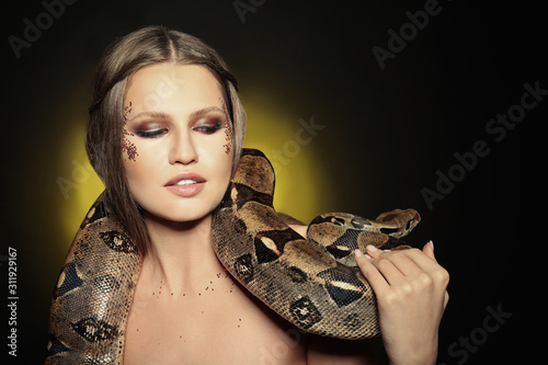 Beautiful woman with boa constrictor on color background. Space for text