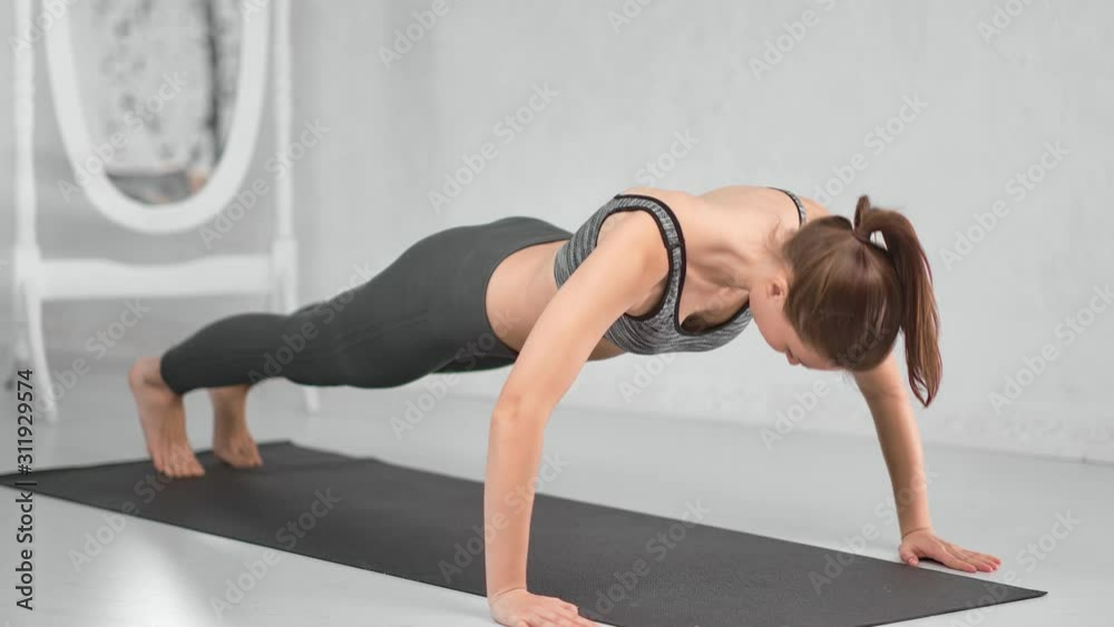Fit muscular strong lady training on floor doing push up at white home interior Fit muscular strong lady training on floor doing push up at white home interior