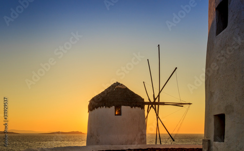 The symbol of Mykonos: seascape at sunset with white famous windmills, Cyclades, Greece. 