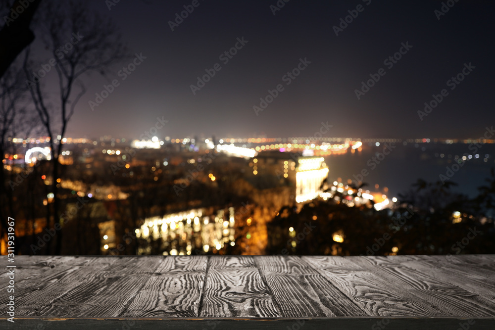 Empty wooden surface and blurred view of modern night city. Bokeh effect
