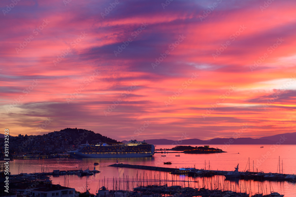 Red sky sunset at Kusadasi Turkey Harbour with Guvercin Adasi castle and cruise ship on the Aegean Sea with Samos Island