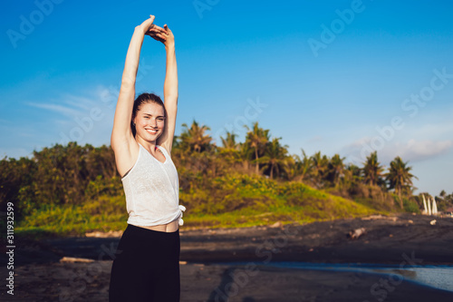 Healthy beautiful woman stretching arms at seaside