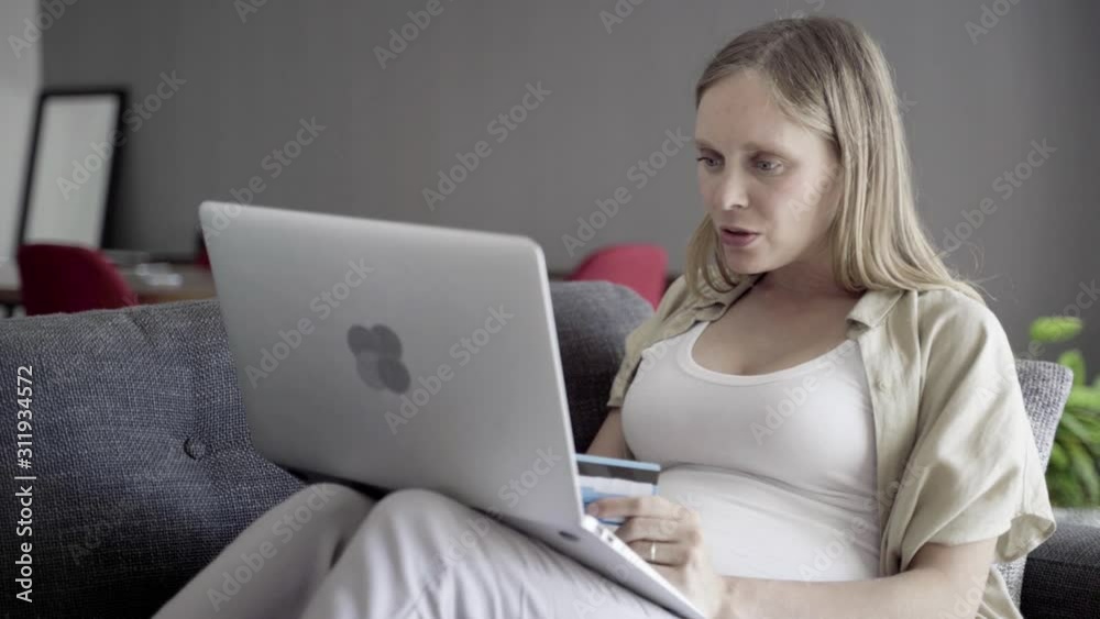 Cheerful pregnant woman shopping online with laptop. Smiling young lady typing card number to make purchase. Pregnancy concept Cheerful pregnant woman shopping online with laptop. Smiling young lady typing card number to make purchase. Pregnancy concept