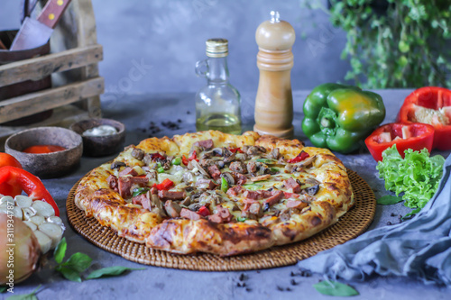 Photo of pizza on the table with ingredients around. Tasty pizza on the wooden background. Homemade pizza. Italian pizza. Delicious pizza. Image
