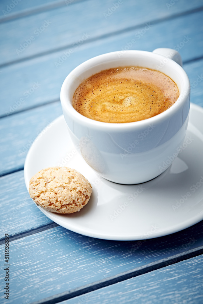 Cup of coffee with amaretti (Italian biscuit) on bright wooden background. Close up. Cup of coffee with amaretti (Italian biscuit) on bright wooden background. Close up.