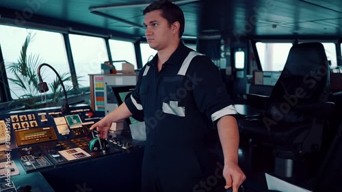 Marine navigational officer during navigational watch on Bridge . He is maneuvering the ship. Work at sea. photo