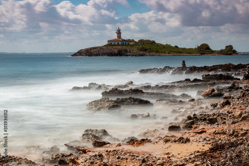 The beautiful coast shore of the island Mallorca in spain with an old and weathered lighthouse - longexposure photography