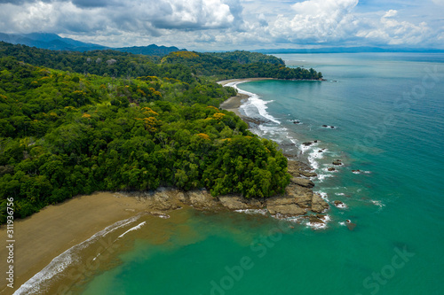 Aerial Drone View of a tropical beach. Sand and water surrounded by lush rainforest