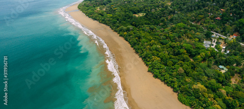 Aerial Drone View of a tropical beach in Costa Rica. Sand and water surrounded by lush rainforest
