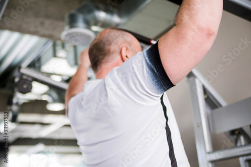 Older man doing pull-up exercise in the gym