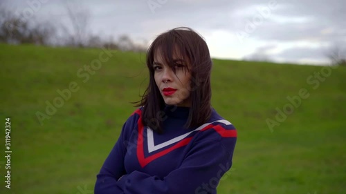 girl with red lipstick in blue sweater against green hill photo
