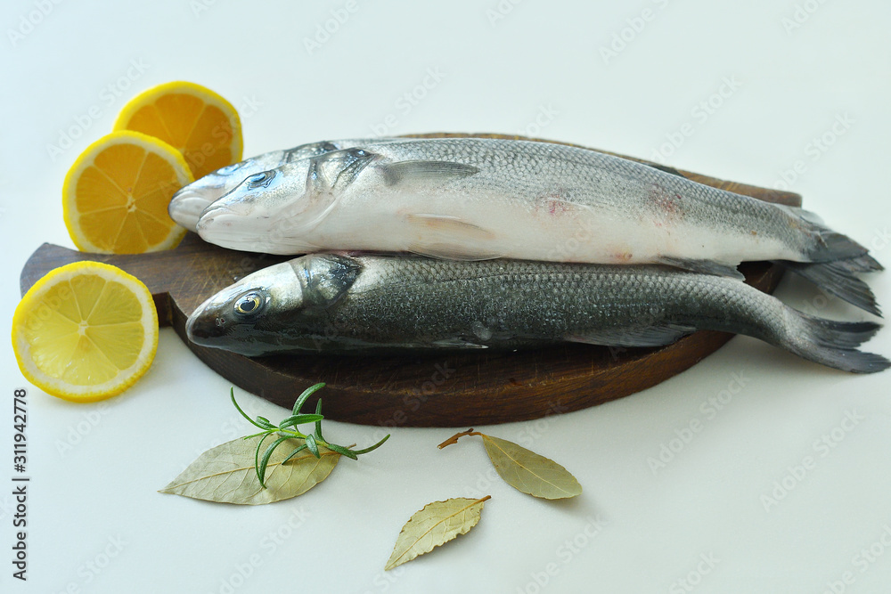Raw fish seabass. Raw fish fillet with spices, herbs, lemon and salt on wooden board ready for cooking, food background. food concept. Mediterranean seafood