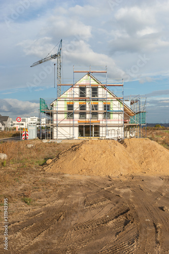 Eingerüsteter Rohbau mit Erdmaterial davor.