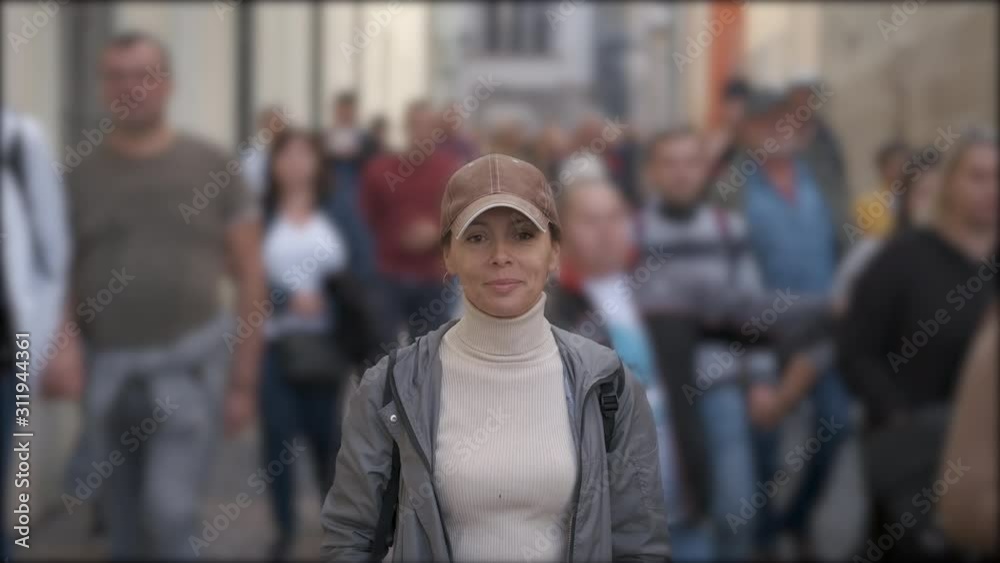 Woman in a crowd of people. A pretty woman stands motionless in a crowd of walking people.