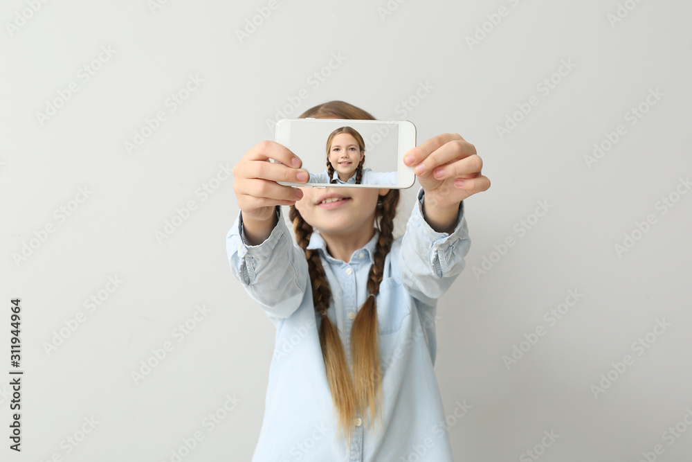 Little girl taking selfie on light background Little girl taking selfie on light background