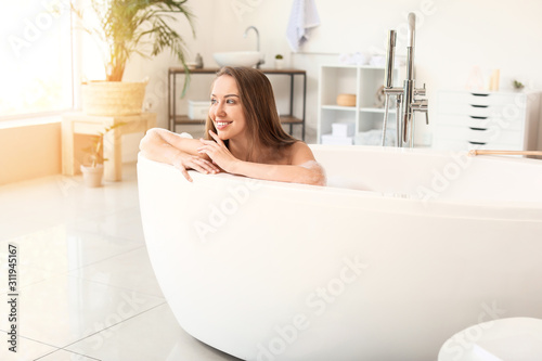 Beautiful young woman relaxing in bathtub