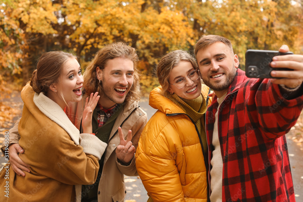 Happy young friends taking selfie in autumn park