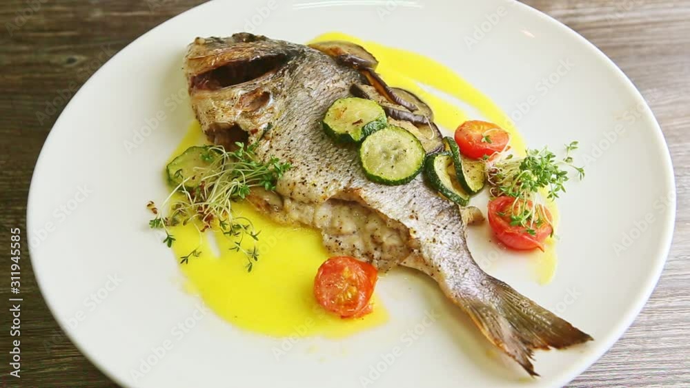tasty roasted whole fish and vegetables spinning around on plate