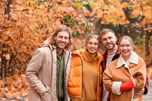 Happy young friends resting together in autumn park