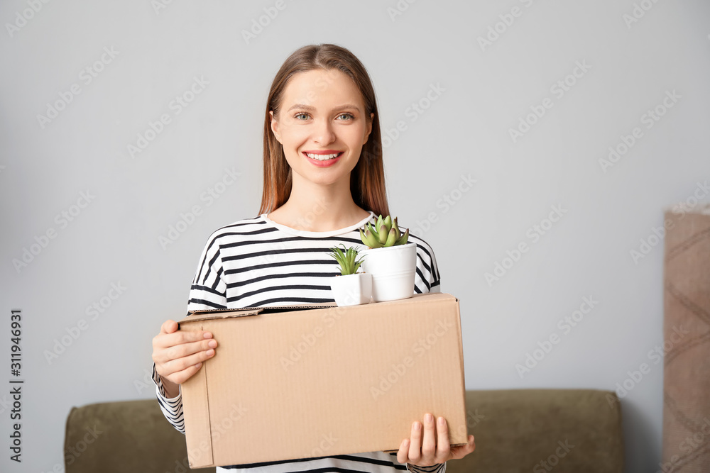 Happy young woman with belongings in new house Happy young woman with belongings in new house