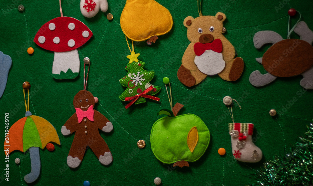 Naklejka premium Felt Christmas tree with felt Christmas toys and a garland. Christmas toys: red star, bear, gingerbread, tree, umbrella, mushroom amanita, apple, pear, dove, boot, mittens, turtle.