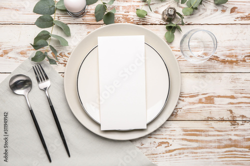 Beautiful table setting with empty menu on white wooden background